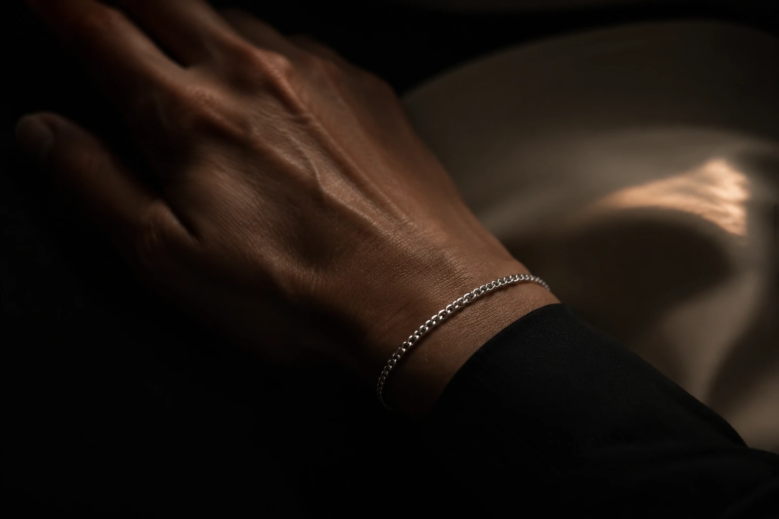 Ein feines Panzerarmband am Handgelenk, seitliches Licht